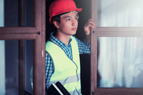 junger asiatischer Mann mit Schutzhelm und Bauweste - Foto, Bild