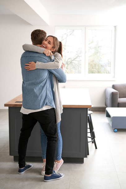 Вертикальный образ очень взволнованной кавказской пары, обнимающейся в своей новой квартире - Фото, изображение
