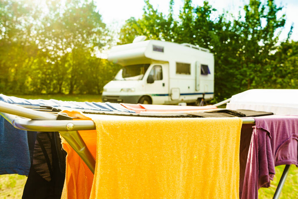 Clothes clean washing laundry hanging to dry on clothesline outdoor, caravan in the background. Camping, adventure concept - Photo, Image