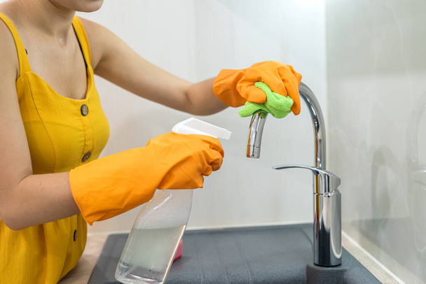 vrouw in gele doek schoonmaken van haar wastafel, huishouden - Foto, afbeelding