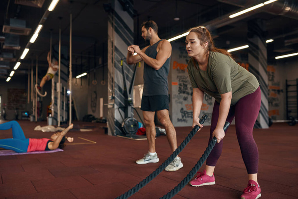 Trainer look at multiethnic girls training in gym - Photo, Image