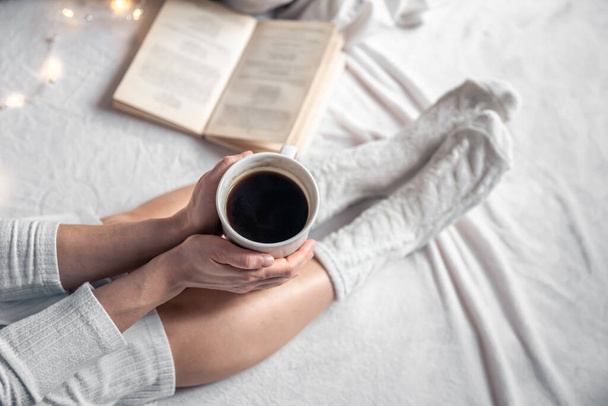 Filiżanka kawy w rękach kobiet w łóżku, widok z góry. - Zdjęcie, obraz