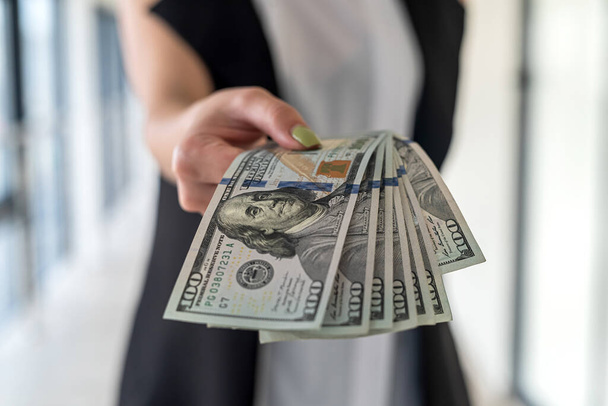 молодая деловая женщина с нами долларовые деньги в руке стоять в офисе. Зарплата или взятка - Фото, изображение