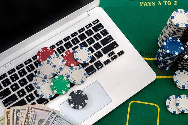 μάρκες πόκερ με χαρτονομίσματα τοποθετημένα σε πληκτρολόγιο φορητού υπολογιστή. Έννοια πόκερ - Φωτογραφία, εικόνα