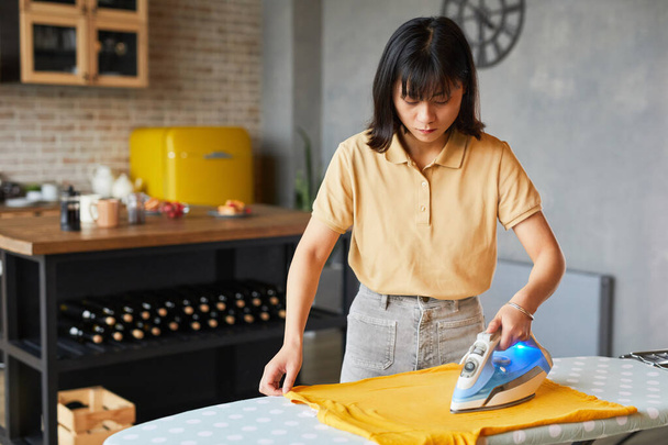 Asiatische Frau bügelt Kleidung zu Hause - Foto, Bild