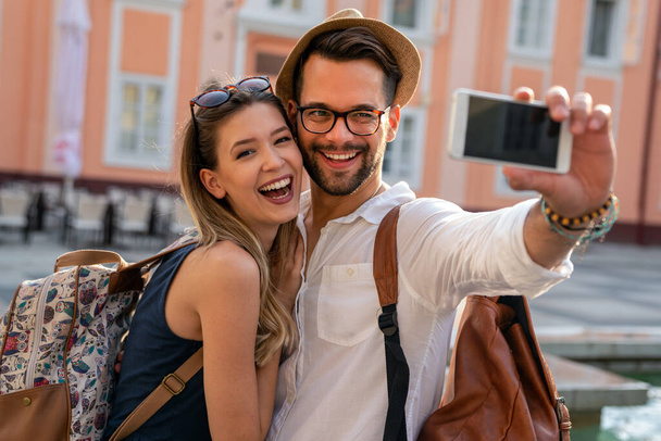 Holidays, vacation, love and friendship concept. Smiling young couple having fun together in city - Fotoğraf, Görsel