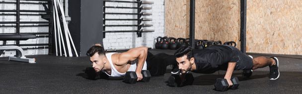 Young interracial friends doing press ups with dumbbells in gym, banner  - Photo, Image