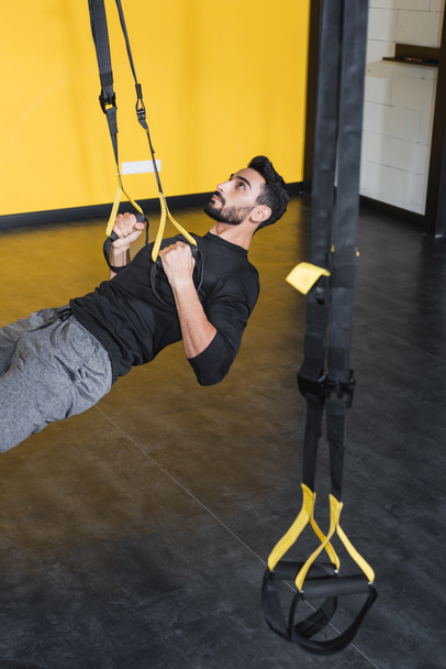 Muslim sportsman training with suspension straps in gym  - Photo, Image
