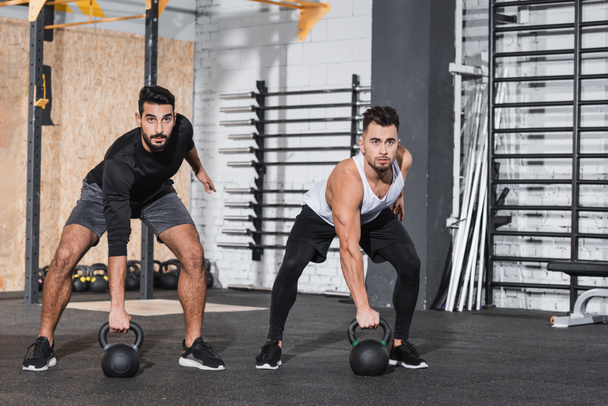 Multiethnic sportsmen training with kettlebells in gym  - 写真・画像