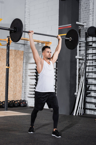 Athletic sportsman lifting barbell in gym  - Фото, зображення