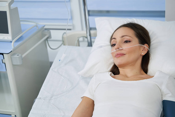 Woman undergoing oxygen therapy in hospital setting - Fotoğraf, Görsel