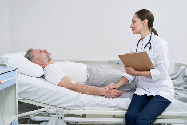 Female clinician examining man undergoing intravenous therapy - Valokuva, kuva