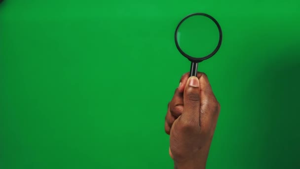 Set 3 Las manos del hombre negro sostienen la lupa y la mueven sobre un fondo de pantalla verde - Metraje, vídeo