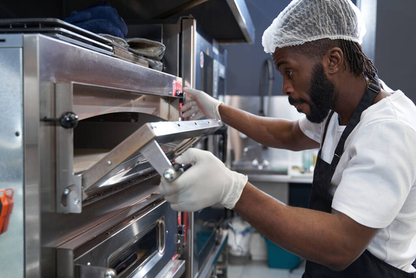 Amerikaanse chef-kok hard werken, bakken eten in restaurant - Foto, afbeelding
