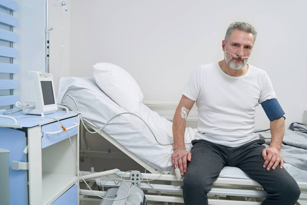 Adult male patient sitting connected to oxygen concentrator - Φωτογραφία, εικόνα