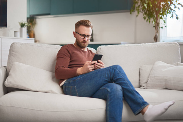 Busy man browsing smartphone at home - Foto, Bild