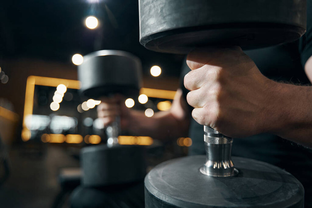 Weightlifter with hand weights seated at gym - Photo, image