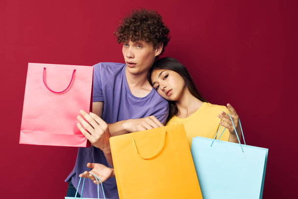 portrait of a man and a woman in colorful T-shirts with bags Shopping Lifestyle unaltered - Фото, зображення