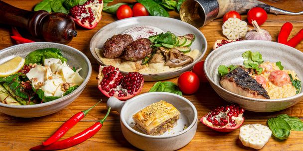 Traditional Georgian cuisine dishes on the table. Side view. Flat lay. A lot of spices and vegetables around, tomatoes and chilli pepper. - 写真・画像