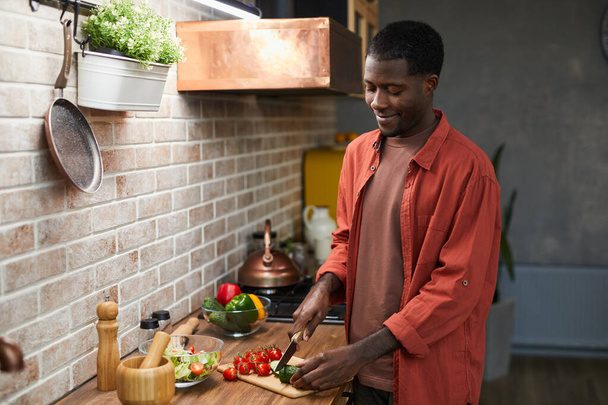 Молодий чоловік готує вдома
 - Фото, зображення