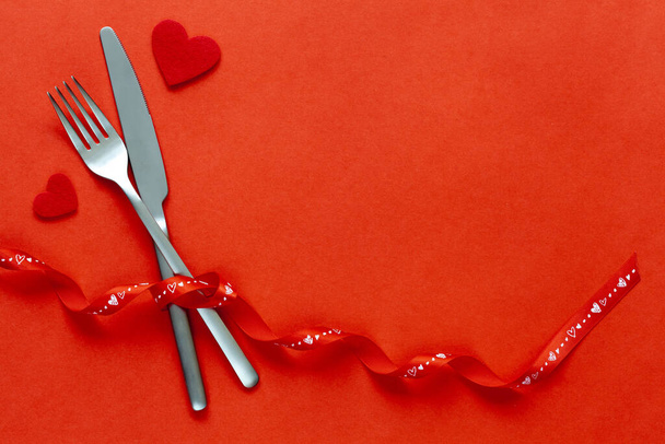 Red background with knife and fork with red belt.  - Foto, imagen