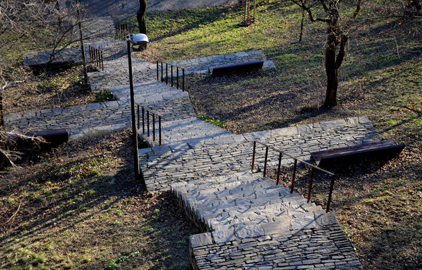 portaikko levähdyspaikoilla. puistossa se johtaa suoraan rinnettä alas lampi. käsittelee black metal kaide. kivi luonto ja betoni polkuja ja portaita. lamput ja puiset penkit - Valokuva, kuva