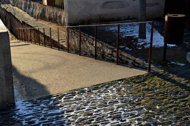 escaleras y rampas para sillas de ruedas de hormigón atractivo. superficies de piedra de pavimentación y escaleras iluminadas por el sol. Barandilla de acero oxidado. manija de plataforma de embarque - Foto, imagen