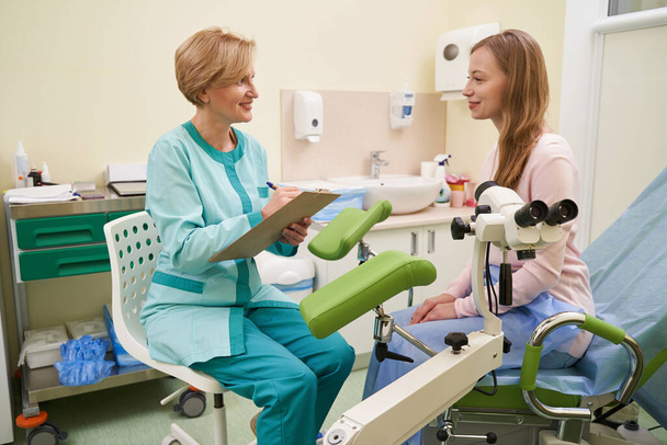 Zufriedene junge Patientin hört ihrem Arzt zu - Foto, Bild