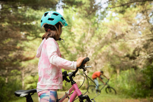 happy child girl riding a bike on natural background, forest or park. healthy lifestyle, family day out. High quality photo - Φωτογραφία, εικόνα
