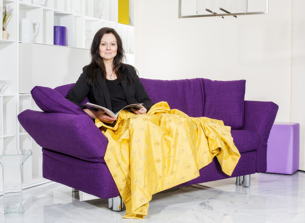 woman on couch with magazine - Valokuva, kuva