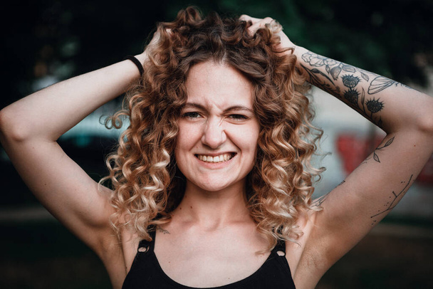 A curly-haired cute woman with tattoos on the street - Valokuva, kuva