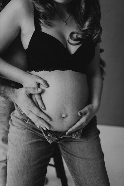 Husband and pregnant wife hug, kiss each other and stroke her tummy  - Foto, Bild
