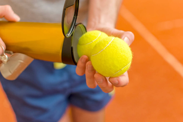 Tennis player holding new pack and two of yellow balls from metal can - Foto, Imagem