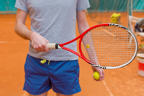 Tennis player holding racket and yellow ball on the tennis court - Photo, image