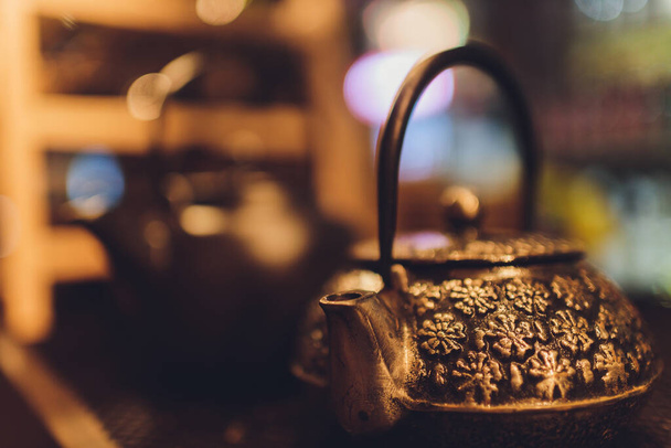 Cast iron black kettle on the table on a brown background. Tea ceremony. - Φωτογραφία, εικόνα