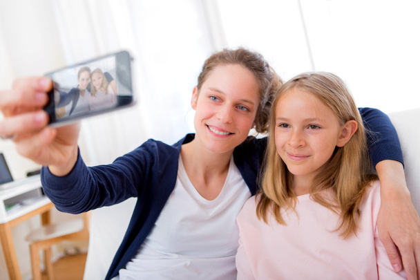 Attractive woman and little sister taking selfie - Foto, immagini
