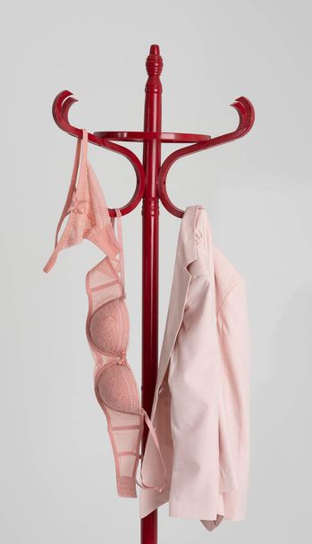 Англия, Великобритания. 2021 год. Розовая куртка и подборка нижнего белья, висящего на крючке вешалки. - Фото, изображение
