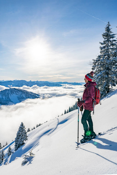 nice senior woman snowshoeing on the Nagelfluh chain above a sea of fog over Bregenz Wald mountains, Hochgrat, Steibis,Bavarian alps, Germany - Foto, afbeelding