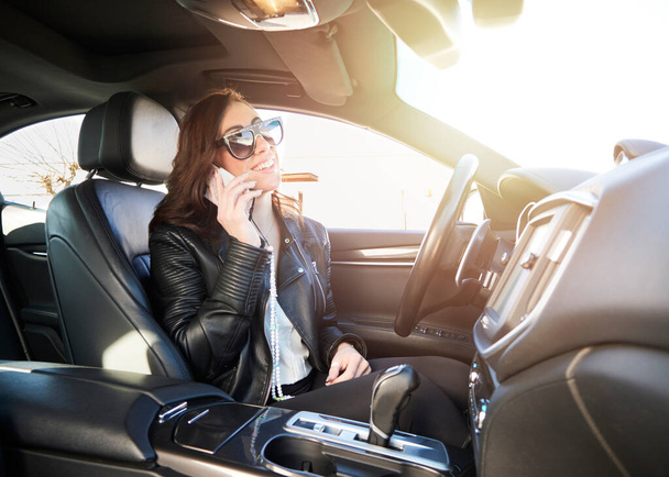 Beautiful woman talking to mobile inside a car - Foto, Imagen