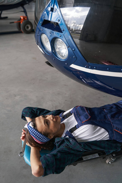 Ingeniera vistiendo uniforme mientras revisa motores de aviones en hangar - Foto, imagen