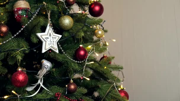 Decoratieve kerstboom met speelgoed en lichtgevende bloemenslinger. Tekstruimte - Video
