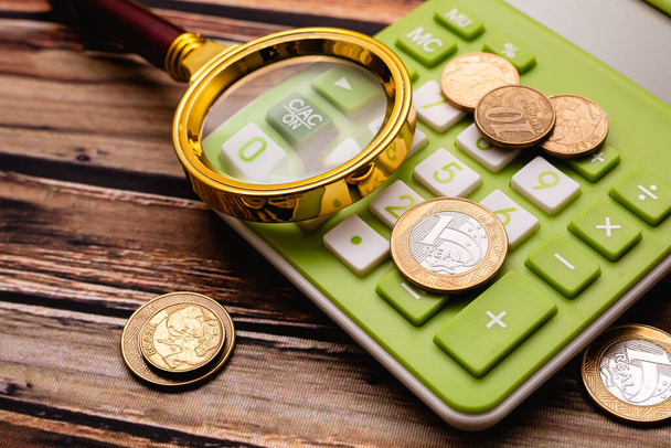 Brazil valuta. A nagyító felett érmék számológép a kép összetételét. Fotó a brazil gazdaságról és a válság pillanatáról magas inflációval. - Fotó, kép
