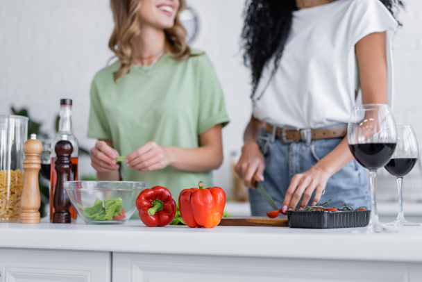 abgeschnittene Ansicht von lesbischem Paar, das in der Küche in der Nähe von Rotweingläsern kocht  - Foto, Bild