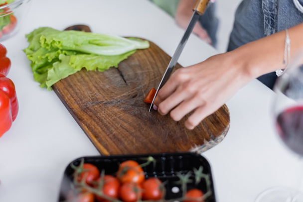 cropped view of woman cutting cherry tomato on chopping board - Photo, Image