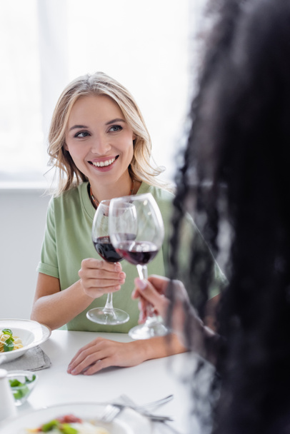 happy lesbian couple clinking glasses of red wine during lunch - Fotoğraf, Görsel