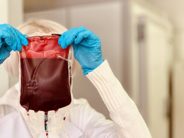 Hands of a medical worker holding a bag of donor blood. - Foto, immagini