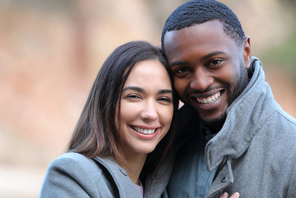 Feliz casal interracial olhando para a câmera sorrindo no inverno - Foto, Imagem