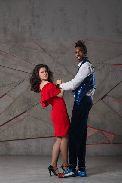 A white girl in a red dress and a black guy are dancing salsa. - Foto, Bild