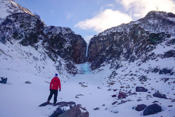 A traveler at the frozen Vilyuchinsky waterfall in Kamchatka peninsula - Zdjęcie, obraz