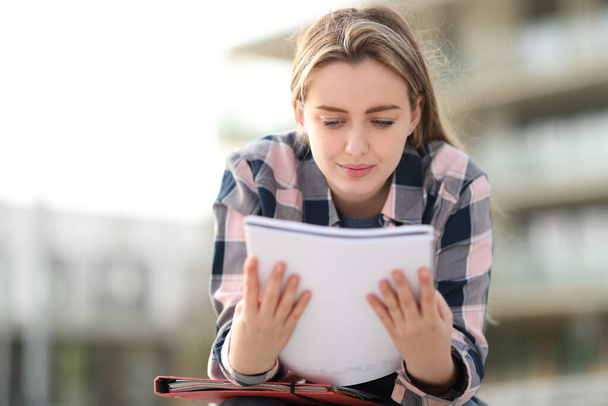 Front view portrait of a student studying reading notes outdoors - Foto, imagen